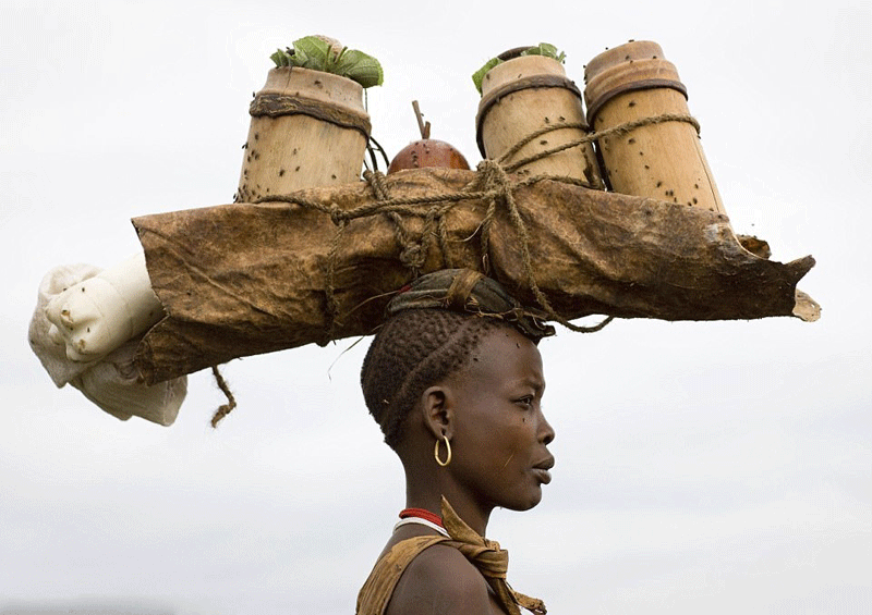 Người phụ nữ Bodi dùng ống tre đưa máu và sữa bò đến lều cho người đàn ông uống mỗi ngày