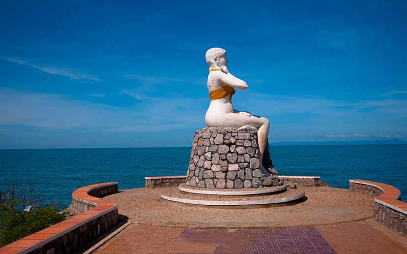 Một pho tượng thiếu nữ to cao dựng tại một mũi đất nhô ra biển