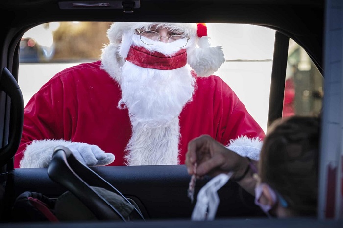 Stan Thompson mặc trang phục ông già Noel và nói chuyện với một đứa trẻ trong xe.
