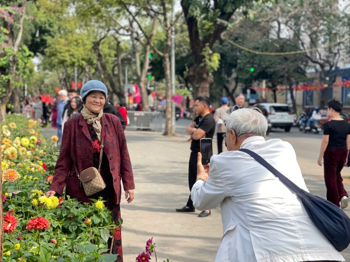 Dọc các vỉa hè quanh hồ, dòng người thảnh thơi tản bộ nối dài, tận hưởng bầu không khí trong lành và tranh thủ ghi lại nhiều khoảnh khắc đời thường bình dị giữa không khí lễ hội mùa xuân.