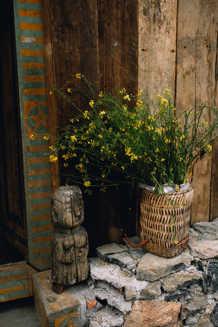 Góc nhỏ mộc mạc trong một ngôi nhà vùng cao với giỏ hoa dại và tượng gỗ trang trí. Ảnh: Long Nhật