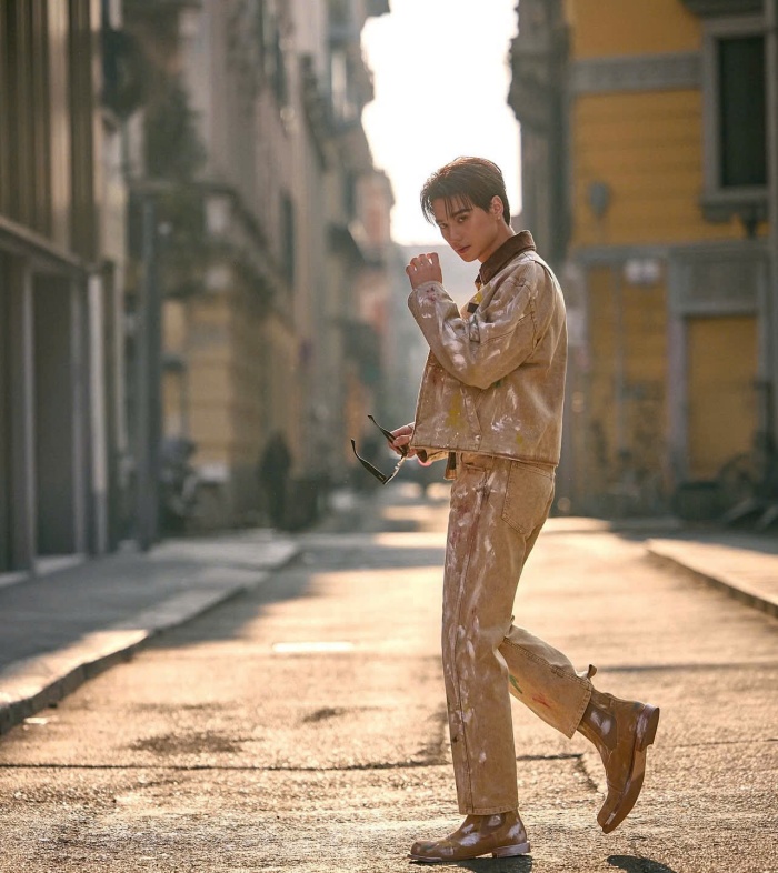 Dù đi cùng nhau, nhưng ở một góc phố Milan, Keng Harit lại chọn cho mình set denim wash màu be với những vệt sơn ngẫu hứng. Thiết kế jacket và quần dài đồng bộ gợi cảm hứng utilitarian - phong cách được biến tấu theo ngôn ngữ thời trang cao cấp, áo phông in chữ và kính râm tông hổ phách giúp outfit thêm phần cổ điển.