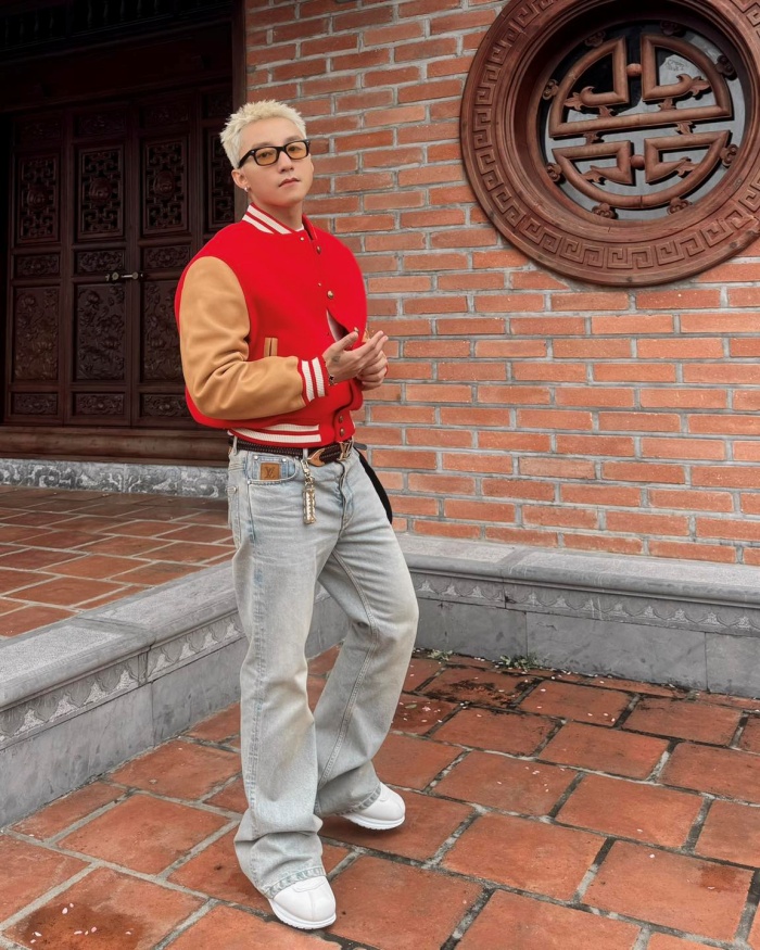 Gam đỏ varsity nổi bật trên nền gạch cổ, mái tóc bạch kim của anh chàng Sơn Tùng và biểu cảm tinh nghịch vẫn là điểm nhấn khó phai.