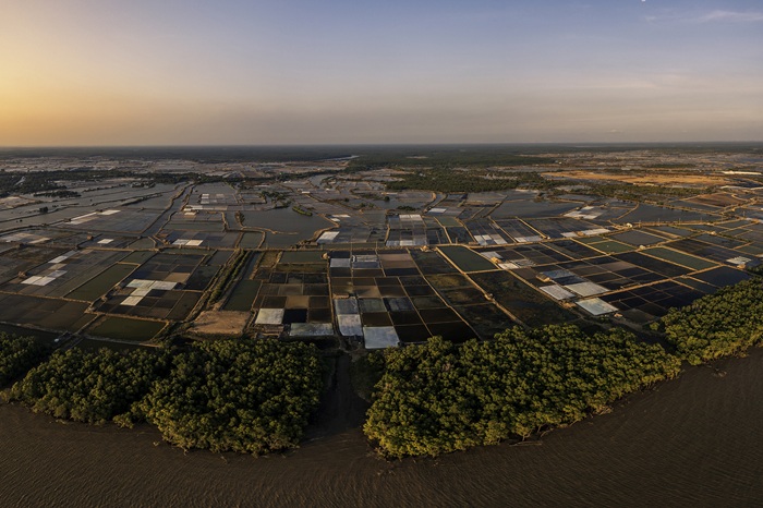 Toàn cảnh cánh đồng muối tại Lý Nhơn nhìn từ trên cao vào thời điểm hoàng hôn, những ô ruộng phản chiếu ánh nắng cuối ngày. 