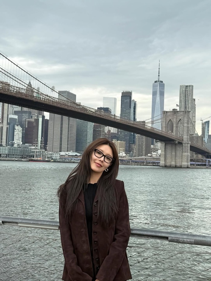 Xuất hiện tại cầu Brooklyn, Sooyoung chuyển sang phong cách cổ điển với áo khoác nâu, kính gọng đen và mái tóc buông tự nhiên. Tổng thể trang phục không quá nổi bật nhưng lại phù hợp với không gian kiến trúc đặc trưng, tạo nên vẻ ngoài chững chạc, tinh tế. Ảnh: Instagram nhân vật