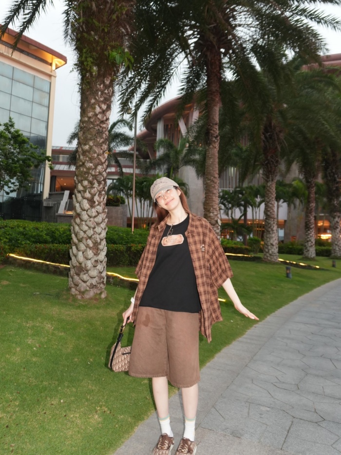 Cô nàng lựa chọn một set đồ mang tông nâu chủ đạo gồm áo sơ mi caro oversize khoác ngoài, áo thun đen bên trong và quần short dáng rộng.