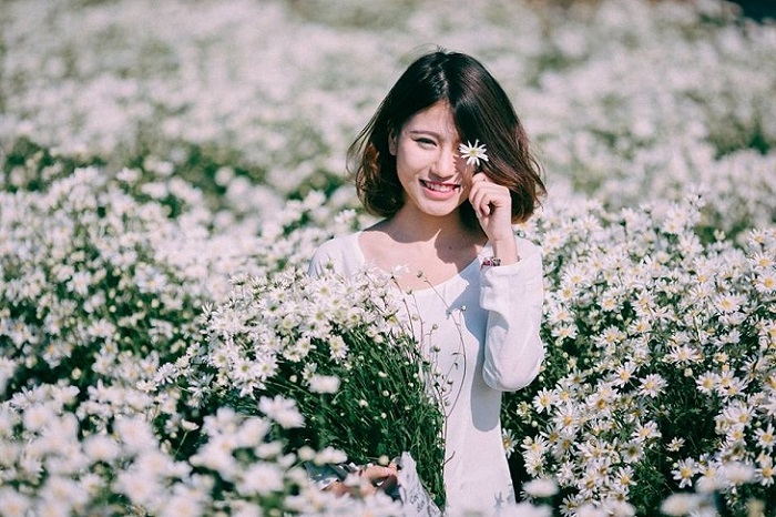 chụp ảnh với cúc họa mi bằng cách tạo dáng dùng hoa che một bên mắt